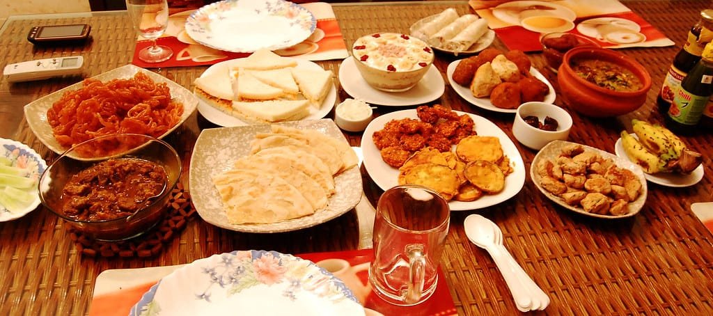 A home iftar table with paratha, jalebi and fried snacks, foods to enjoy in moderation during Ramadan