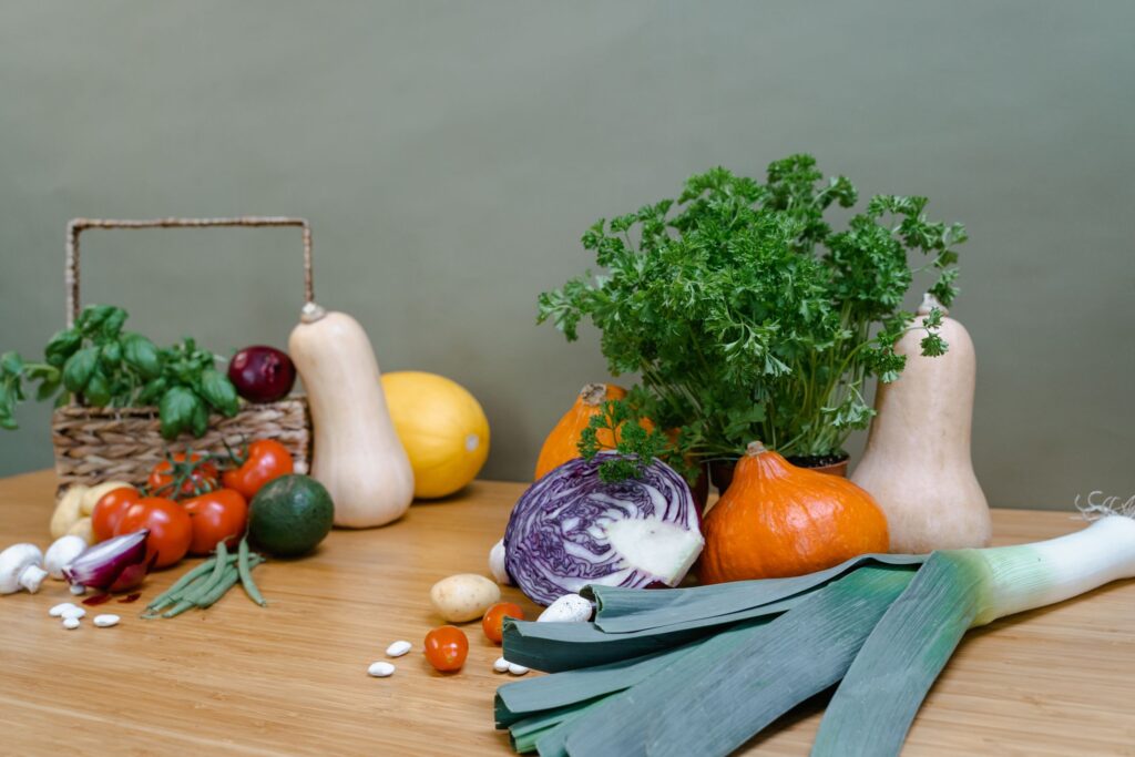 Kidney disease diet: fresh vegetables, gourds, and culinary herbs arranged on a wooden table