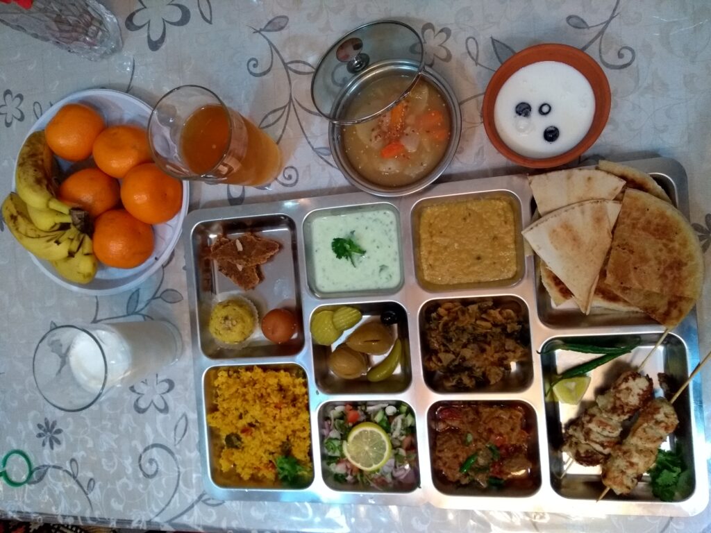 A complete Pakistani thali featuring roti, rice, daal, and sabzi served in traditional steel bowls